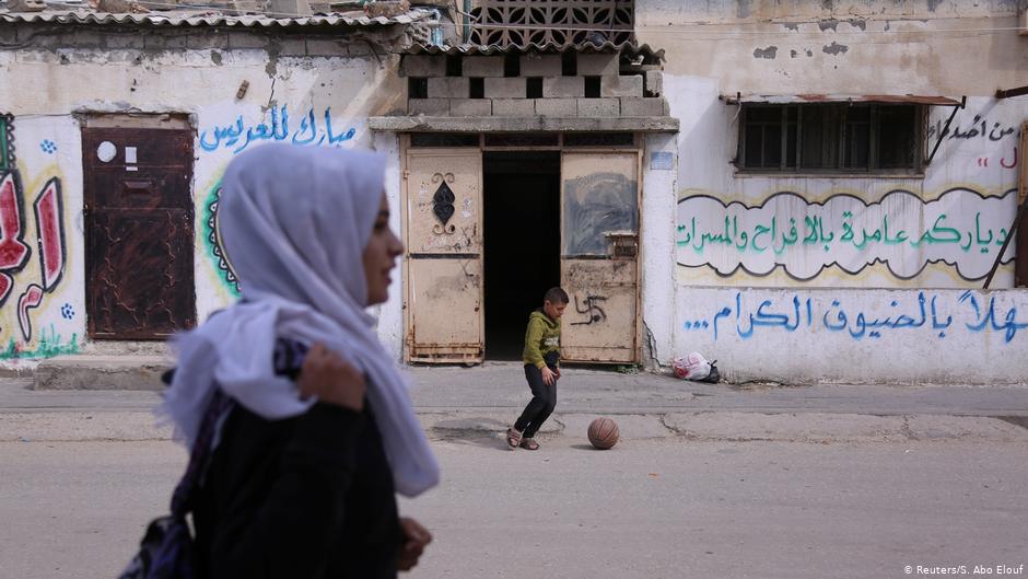 A boy plays ball as Wessal Abu Amra walks home from school in Gaza City (photo: Reuters/Samar Abo Elouf)
