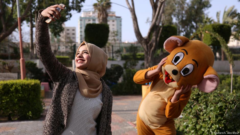 Wessal take a selfie with a person wearing a costume in a public park in Gaza City (photo: Reuters/Samar Abo Elouf)