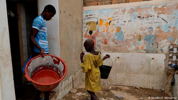 Moussa, a talibe, from Futa, carries a bucket of water to take a shower (photo: Zohra Bensemra)