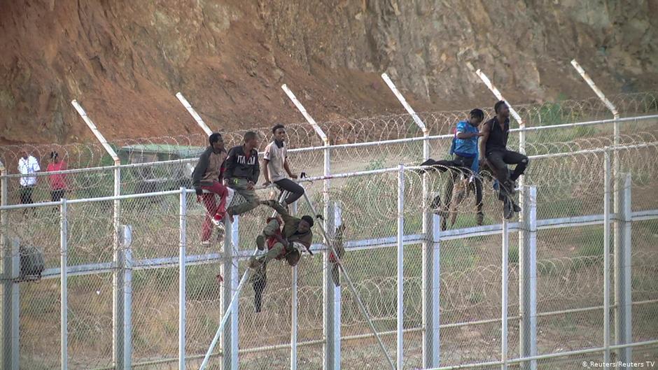 مهاجرون أفارقة يصعدون السياج الحدودي الفاصل بين المغرب وجيب سبتة الإسباني في شمال إفريقيا.  (photo: Reuters/Reuters TV)