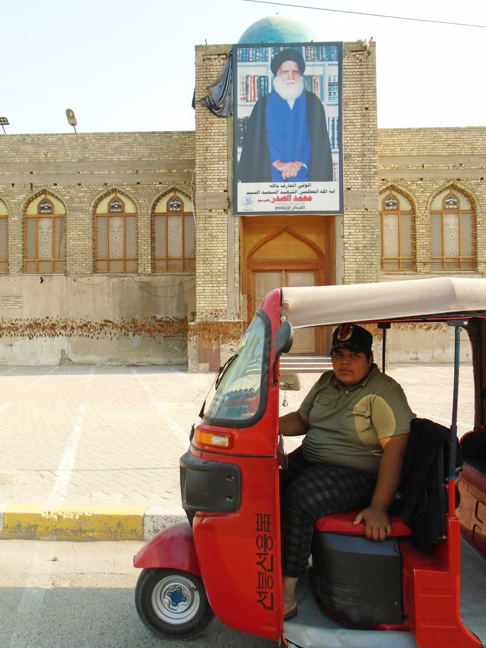 حسين يجلس بثقة في توك توك ذي لون أحمر ناري بغداد - العراق. Foto: Birgit Svensson