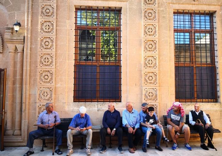 People sit in the shade in front of the Mor Barsamo Church in Midyat (photo: Marian Brehmer)
