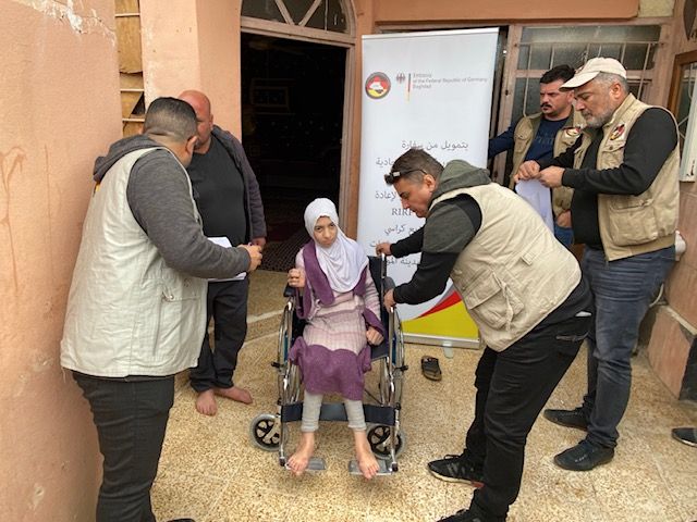 Amal sits in her new wheelchair, to her right stands Faris the construction engineer (photo: RIRP)
