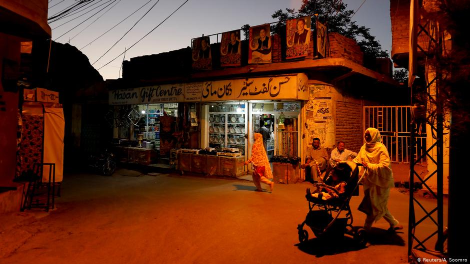Resident walk past a shop during sunset hours along a street in Mariabad, Quetta(photo: Reuters/A. Soomro)