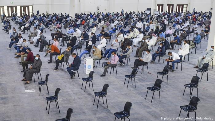 A hall for testing is lined with hundreds of well spaced seats. Hundreds in masks sit and wait
