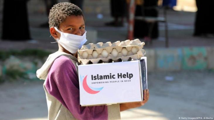 Child wearing a face mask carries a box of aid in Taez, Yemen (photo: Getty Images/AFP/A. Al-Basha)