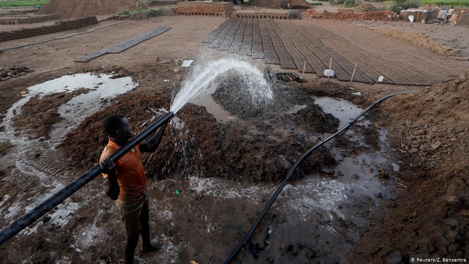 Zaki El-Dine, 24, a brick-maker, pours water from the Nile river onto a patch of mud to make bricks on Tuti Island, Khartoum, Sudan, 12 February 2020 (photo: REUTERS/Zohra Bensemra)  