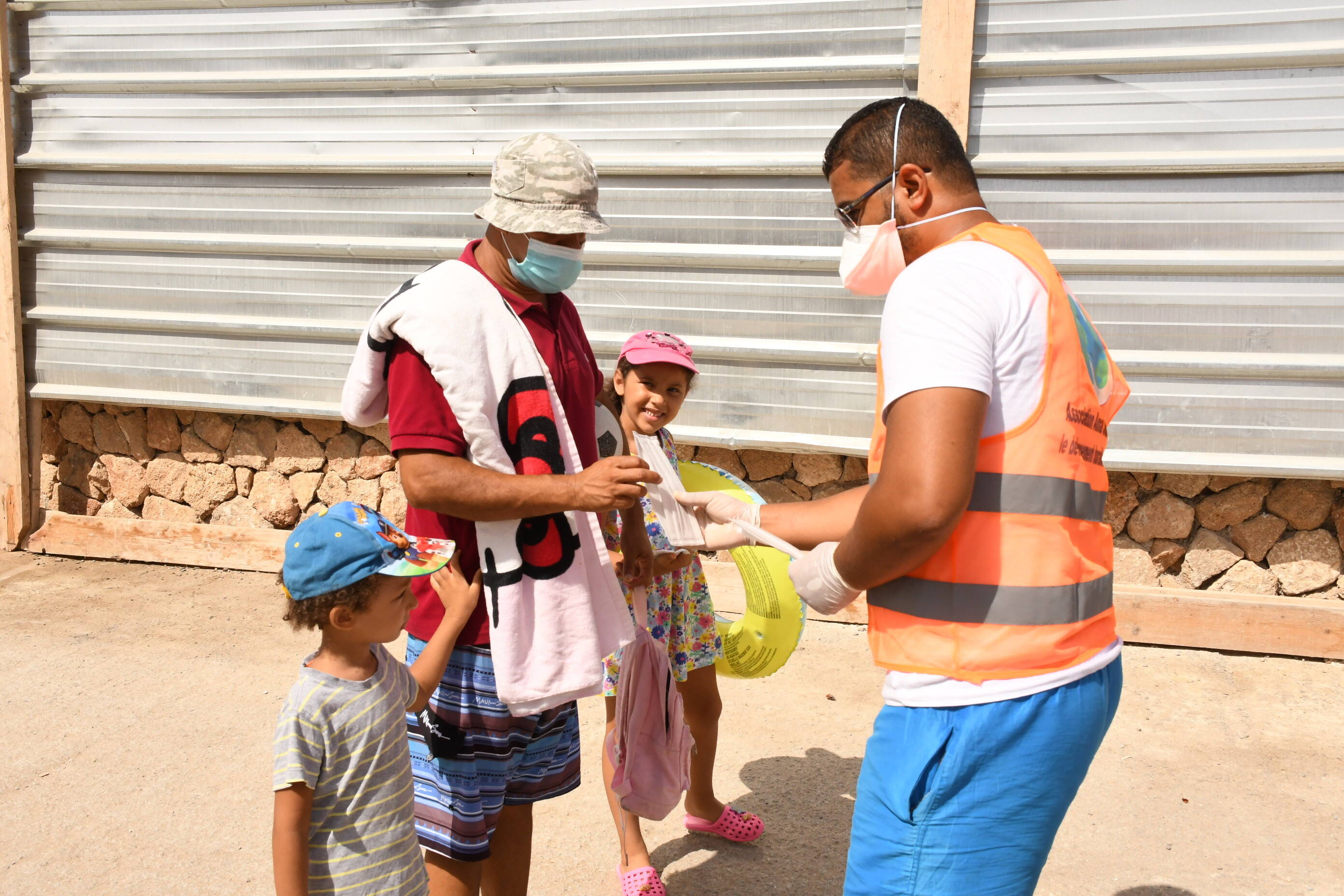 A health worker distributes a mask to a man on a beach in Rabat, Morocco, on 27 August 2020 (photo: imago images/Xinhua | Chadi via www.imago-images.de)