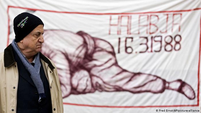 Man stands in front of a poster remembering the chemical weapons attack on Halabja (photo: Fred Ernst/AP/picture-alliance)