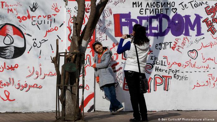 Eine junge Frau nimmt ein Foto vor einem Graffiti in Kairo auf. Foto: picture-alliance/AP Photo/Ben Curtis