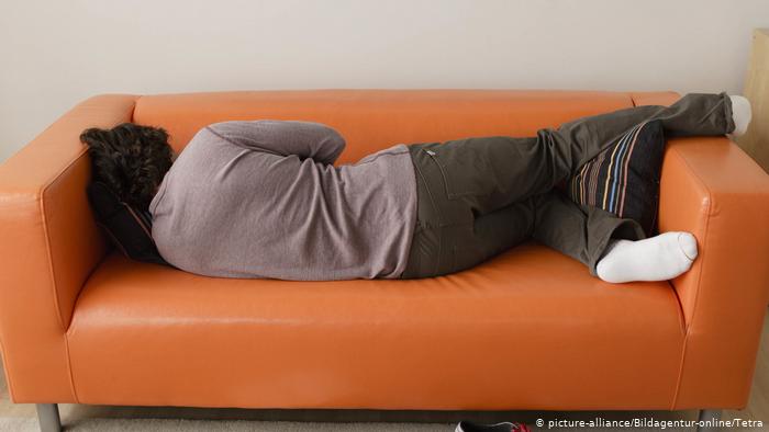 Schlafende Person auf einem orangefarbenen Sofa (photo: picture-alliance/Bildagentur-online/Tetra)