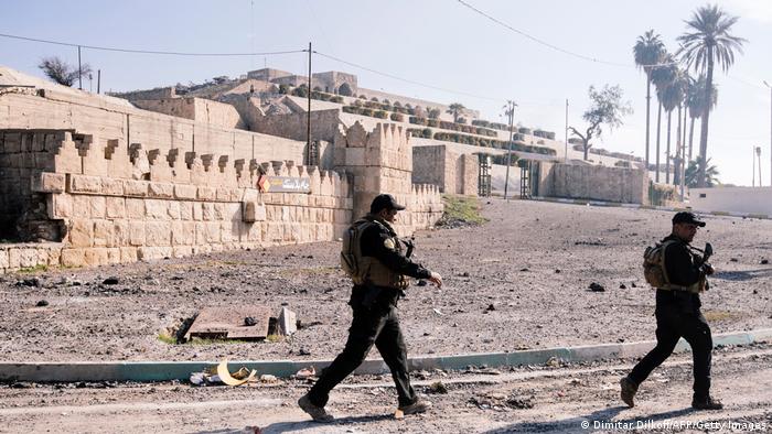 Soldiers with rifles patrol in front of the ruins of the Jonah shrine