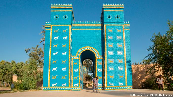 Large turquoise-coloured gate with gold and white decorations, person in front