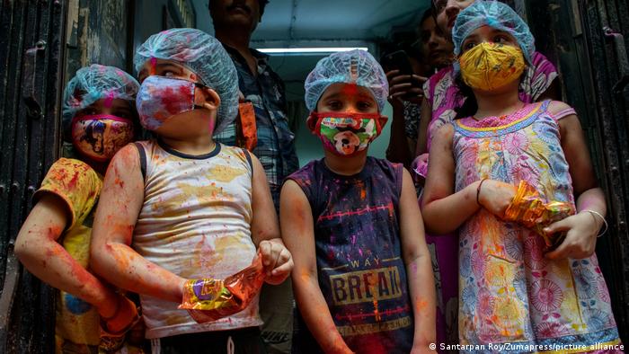 Children in masks and caps hold bags of coloured powder (photo: Santarpan Roy/Zumapress/picture-alliance)