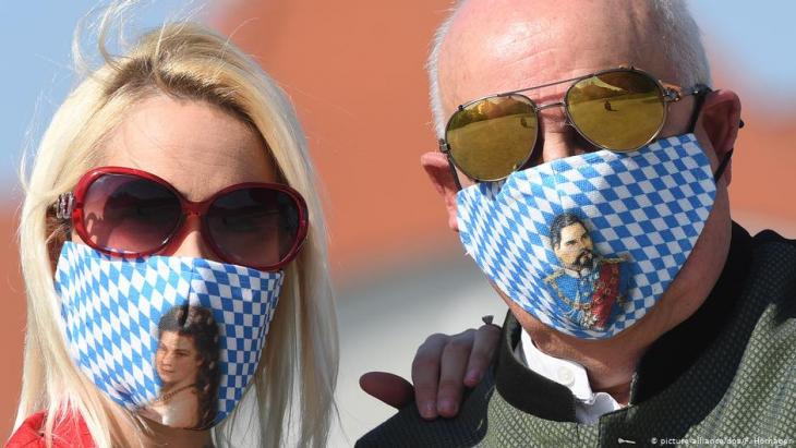A man and a woman wear face masks with traditional Bavarian patterns (photo: picture-alliance/dpa/F. Hornager)