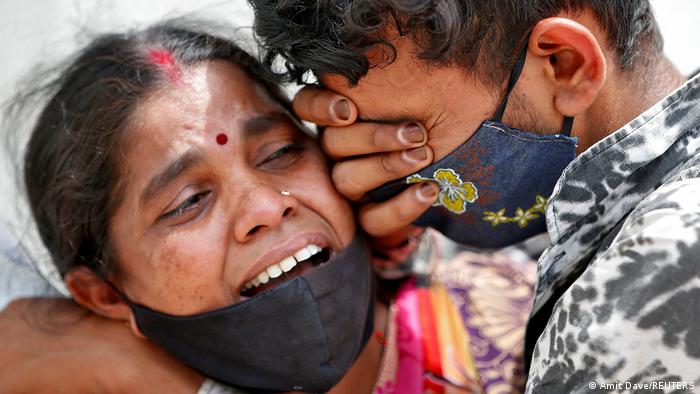 A woman mourns with her son after her husband died due to the coronavirus