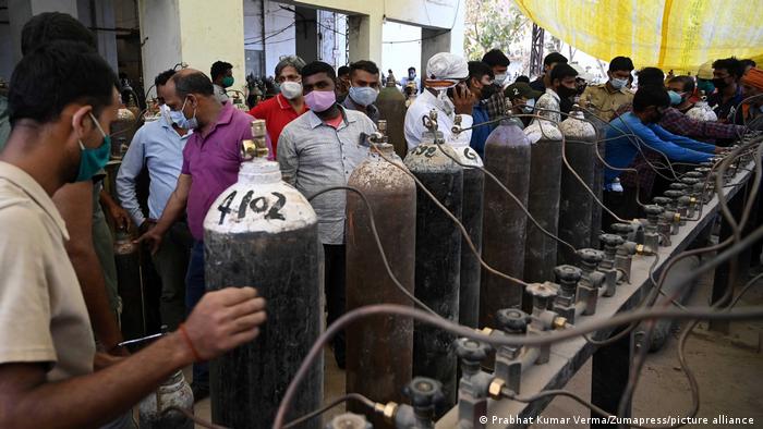 Family members of COVID-19 patients queue to take cylinders filled with medicated oxygen