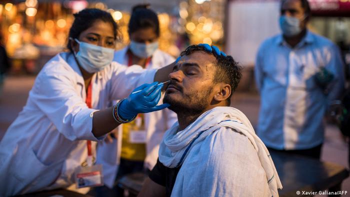 A health worker collects a nasal swab sample from a Hindu devotee