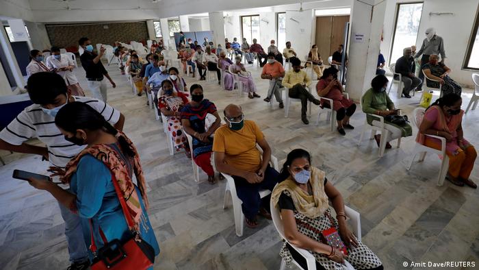 People sit in a waiting area to receive a dose of COVISHIELD