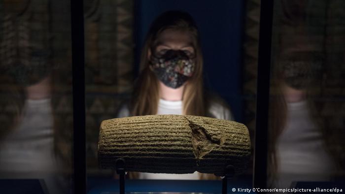 A museum staff member looks at the Cyrus Cylinder in a display case ahead of the 'Epic Iran' exhibition
