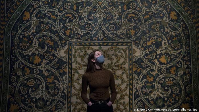 A museum staff member standing in front of a full-size reproduction of a tilework from 1877 at the 'Epic Iran' show at the V&A in London