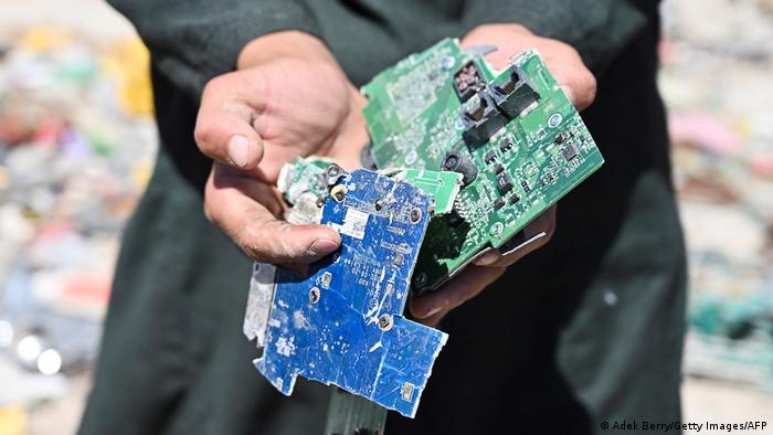 A man holds bent U.S. computer motherboards in Bagram