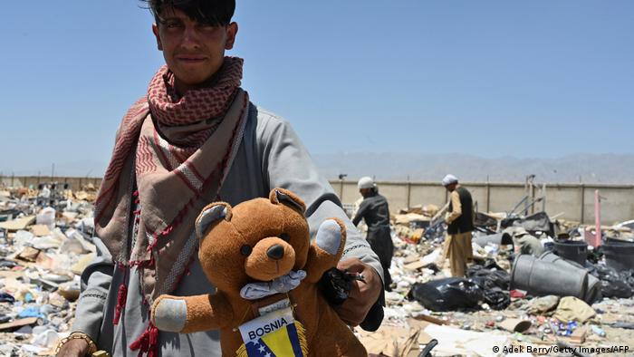 A man with a teddy bear on Bagram junkyard