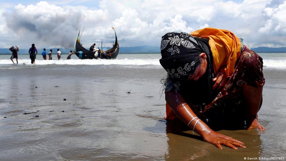 An exhausted Rohingya refugee woman touches the shore after crossing the Bangladesh-Myanmar border by boat through the Bay of Bengal, in Shah Porir Dwip, Bangladesh, 11 September 2017 (photo: REUTERS/Danish Siddiqui)