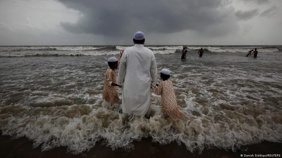 A Muslim man walks hand in hand with children at a beach as monsoon clouds gather in Mumbai, 22 July 2011 (photo: REUTERS/Danish Siddiqui)
