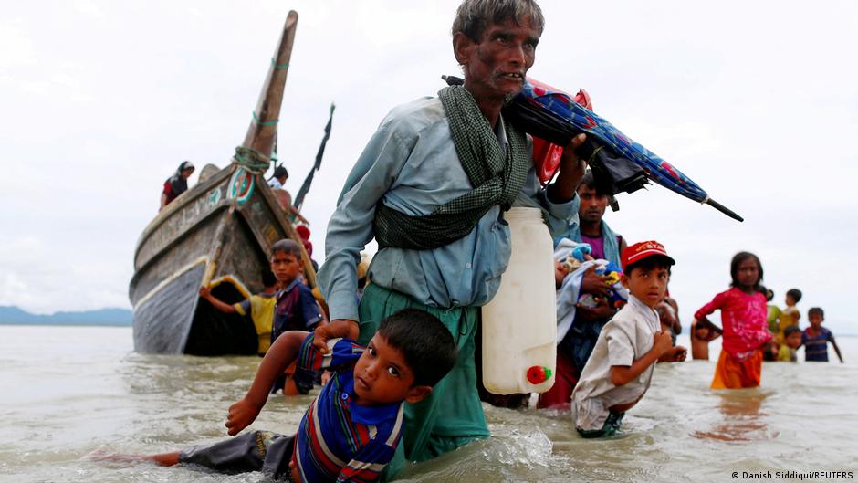 A Rohingya refugee man pulls a child as they walk to the shore after crossing the Bangladesh-Myanmar border by boat through the Bay of Bengal in Shah Porir Dwip, Bangladesh, 10 September 2017 (photo: REUTERS/Danish Siddiqui)