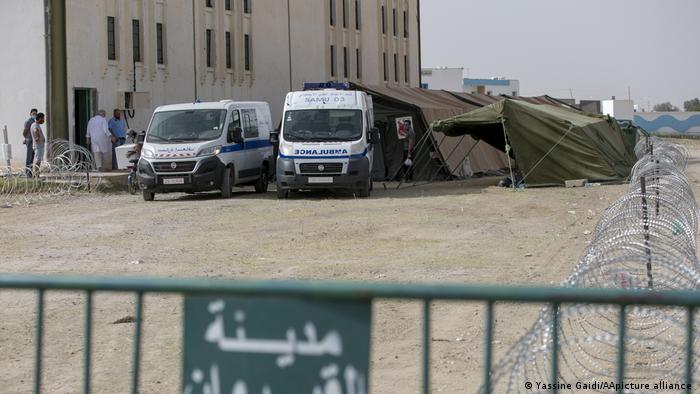 Two ambulances parked in front of two tents, building to the left, barbed wire to the right (photo: Yassine Gaidi/AA/picture-alliance)