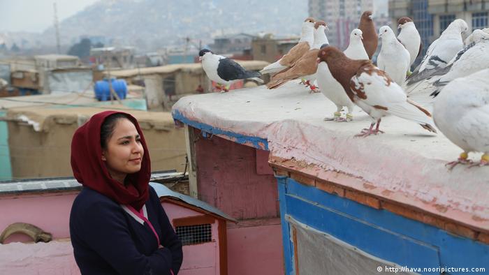 A woman on a Kabul rooftop looking at pigeons