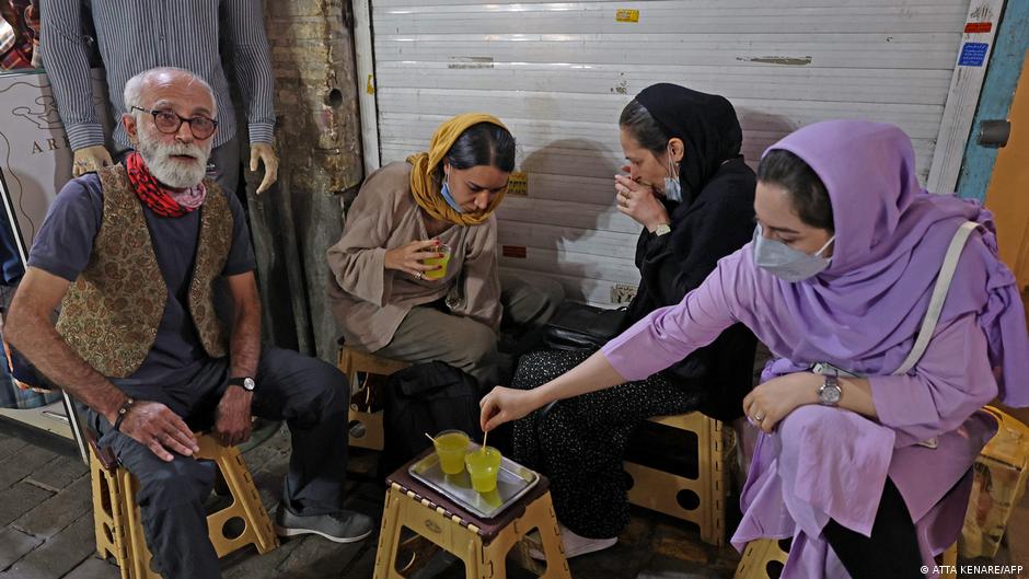Owner Kazem Mabhutian (L), 63, drinks tea with his costumers outside his smallest and oldest teahouse tucked away in an alleyway of the Grand Bazaar in the Iranian capital Tehran on 20 September 2021 (photo: Atta Kenare/AFP)