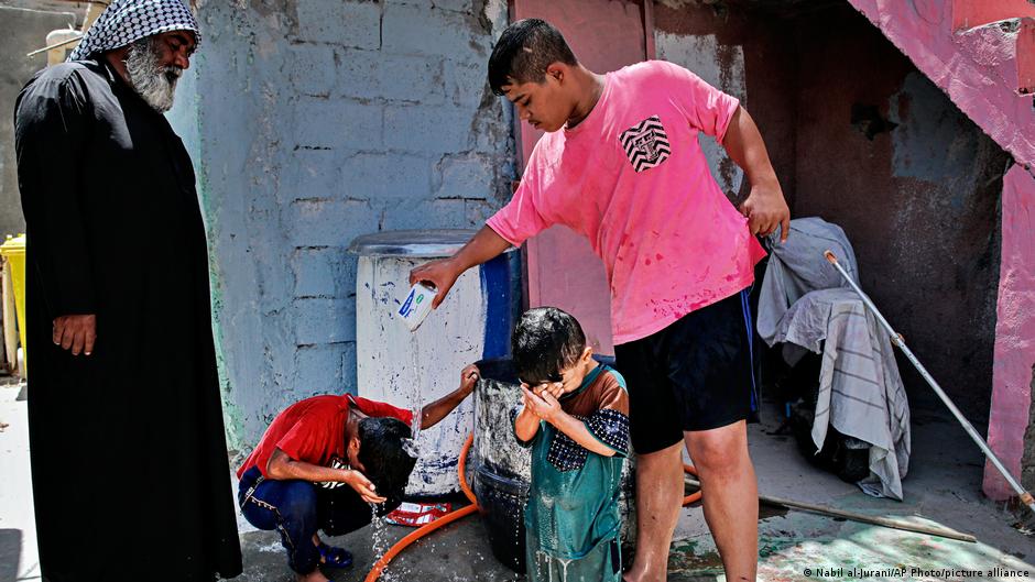 Children cool themselves with water during a power outage in Basra, Iraq, Tuesday, 29 July 2021 (photo: AP Photo/Nabil al-Jurani)