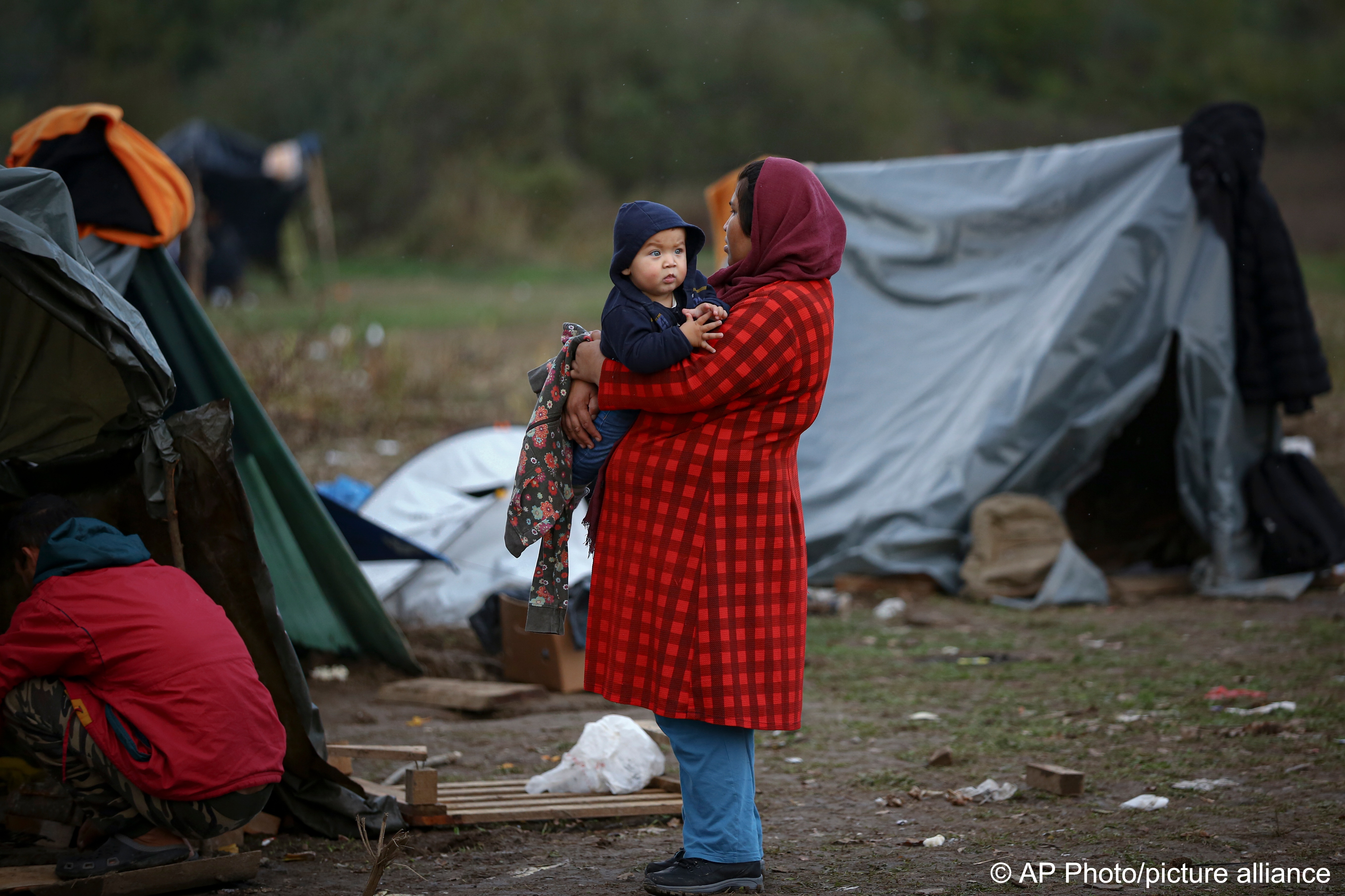 Eine Migrantin hält ein Baby in einem Behelfslager für Migranten, die hauptsächlich aus Afghanistan stammen, in Velika Kladusa, Bosnien, 12. Oktober 2021; Foto: AP Photo
