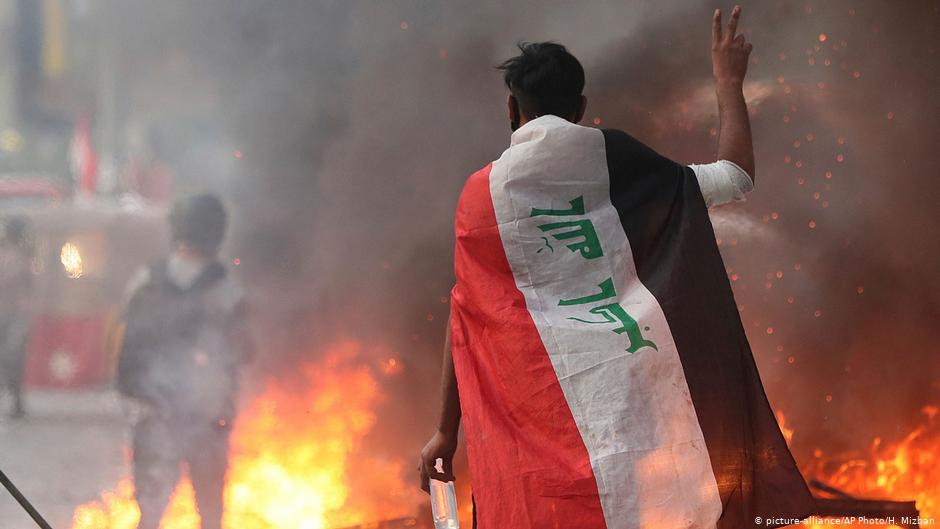 A young man draped in the Iraqi flag during one of the 2019 protests in Iraq (photo: picture-alliance/AP Photo/H. Mizhan)