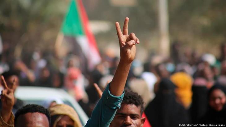 A pro-democracy activist raises his hand in protest at the military coup in Sudan (photo: Ashraf Idris/AP Photo/picture-alliance)