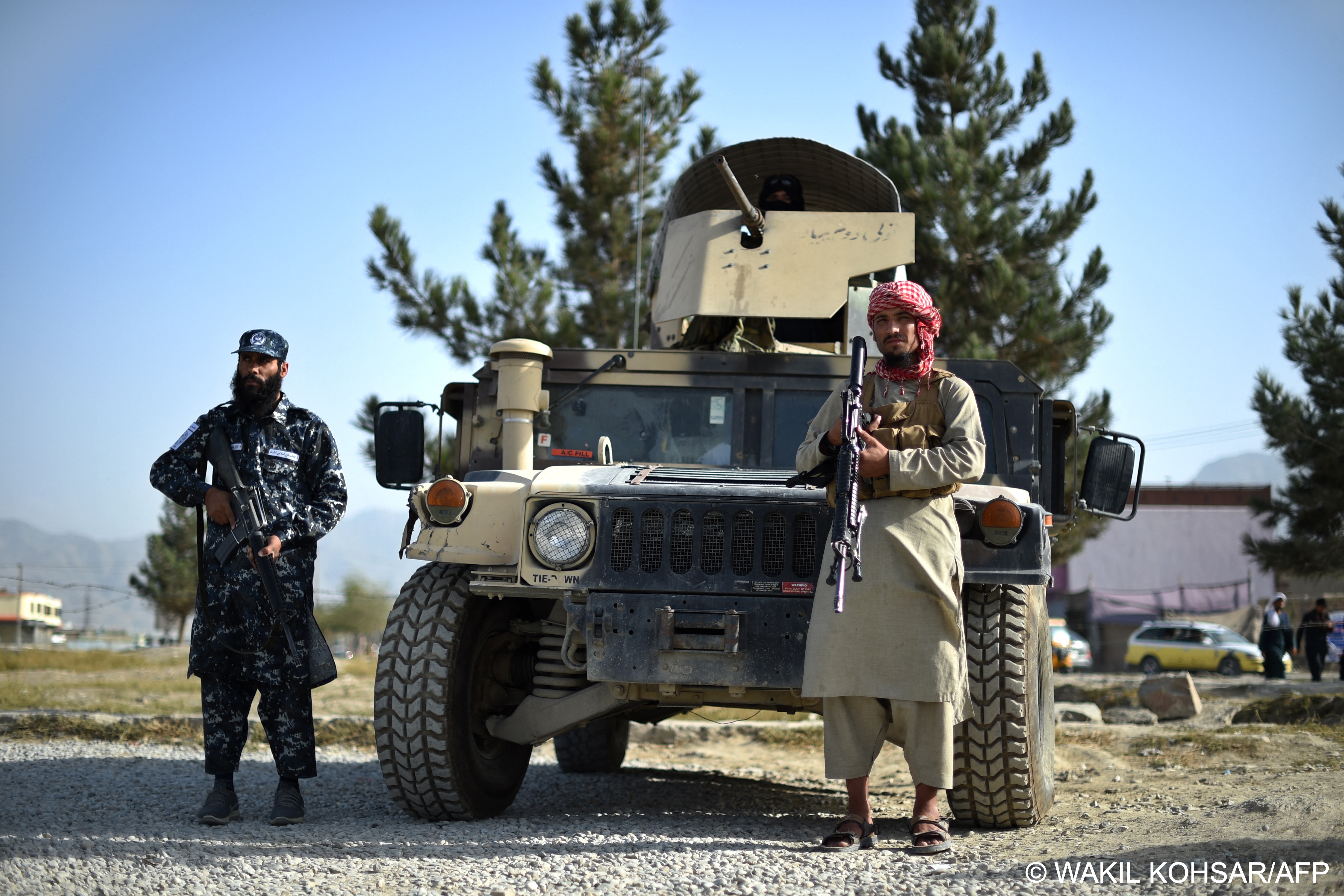 Taliban fighters pose with an armoured vehicle and munitions (photo: Wakil Kohsar/AFP) 