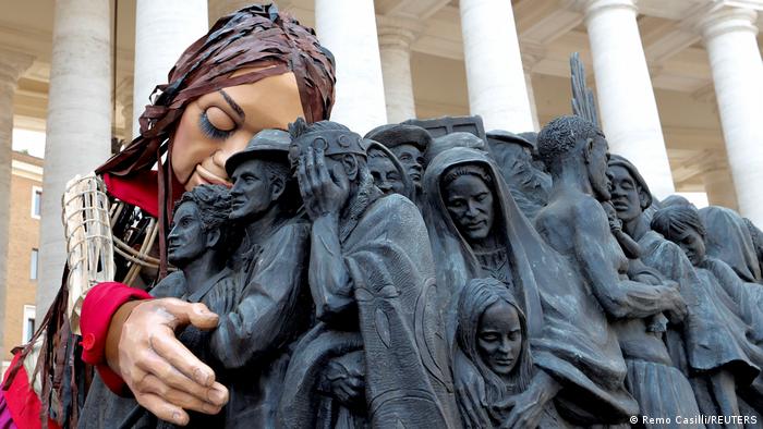 Little Amal umarmt die Bronzestatue Angels Unaware auf dem Petersplatz im Vatikan, 10.09.2021; Foto: Reuters/Remo Casilli/TPX Images of the Day