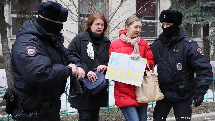 Russian police escort two women protesters away from a building 