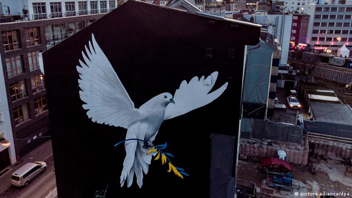 Huge painting of dove of peace on outside wall of Frankfurt building, with olive branch with Ukrainian flag colours in claws