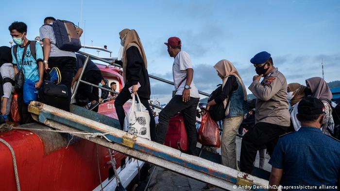 People board ferry on gangway, wearing masks to prevent the spread of the coronavirus