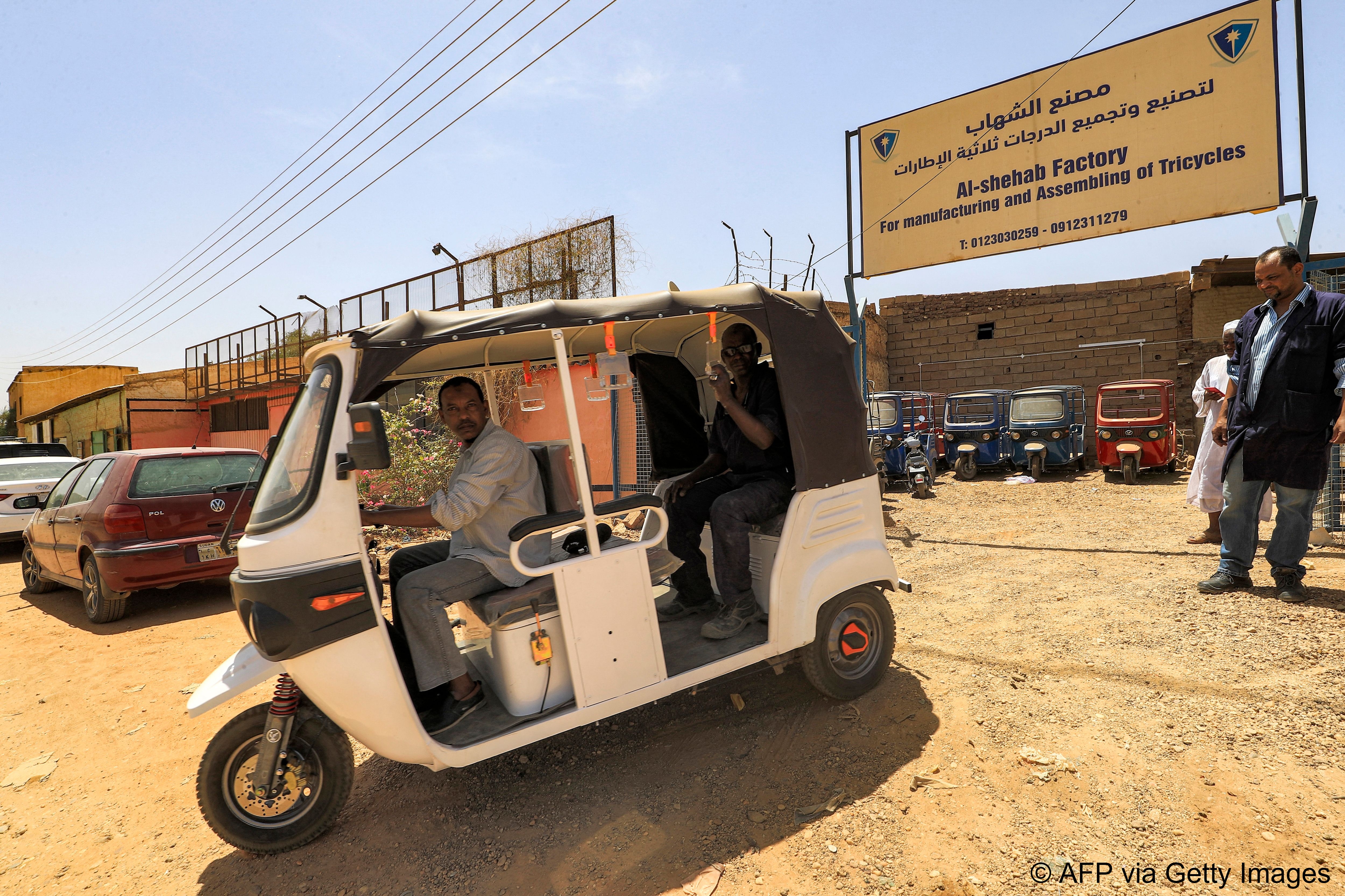 Sudanese workers test a new electric tuk-tuk.