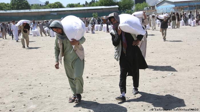 Men in Kabul receive food deliveries from China and carry them away in sacks