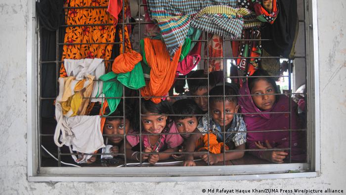 A group of children smiles at the photographer through the window of a flood relief centre