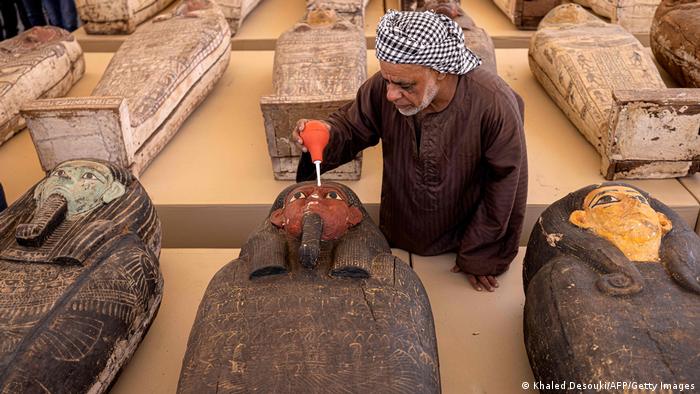A labourer uses a hand air blower to brush dust off one of the sarcophagi found in a cache dating to the Egyptian Late Period (around the fifth century BC), on display after its discovery by a mission headed by Egypt's Supreme Council of Antiquities, at the Bubastian cemetery at the Saqqara necropolis, southwest of Egypt's capital on 30 May 2022