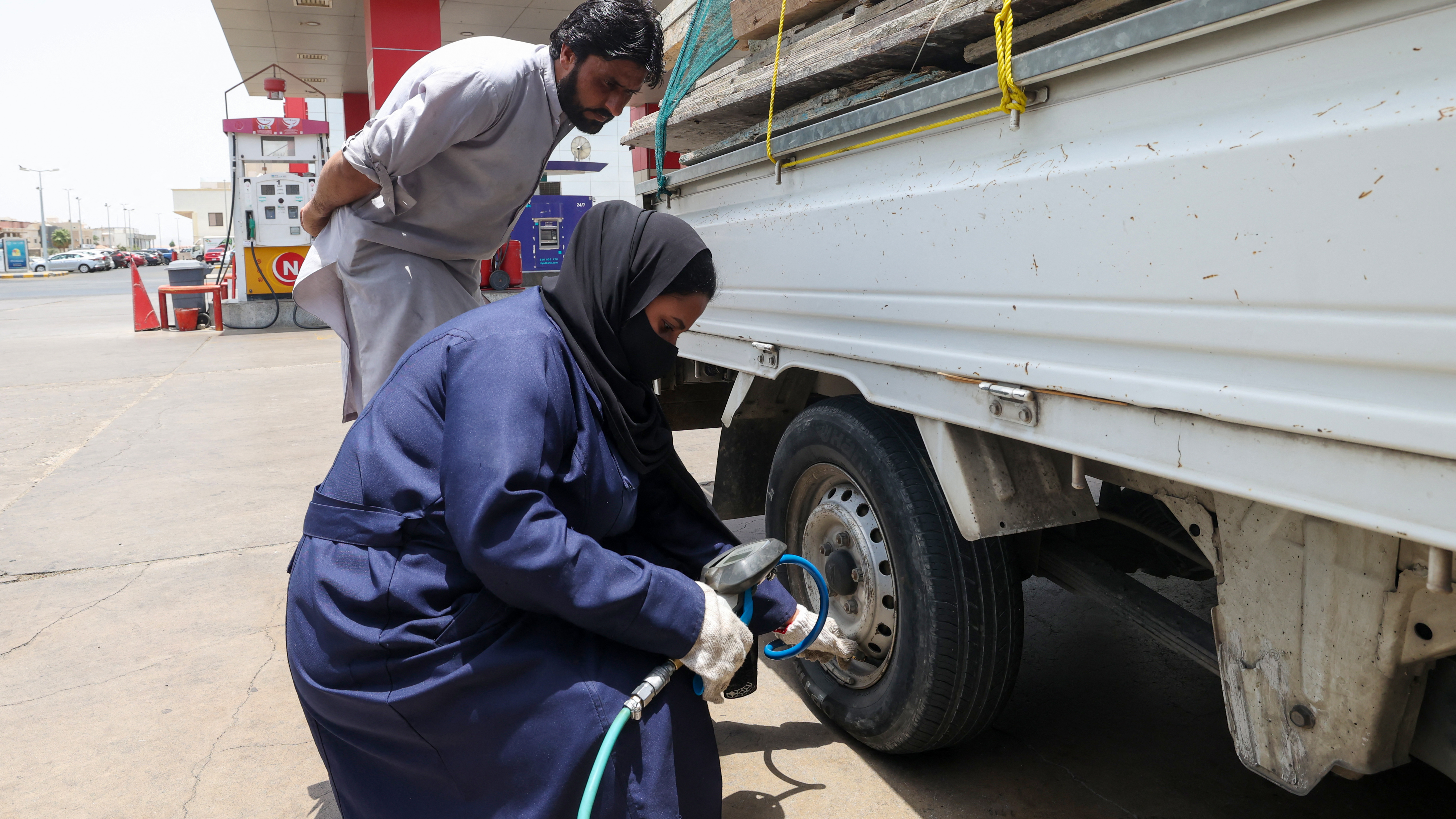 A male customer watches over Ghada Ahmed as she works on his truck (photo: Fayez Nureldine/AFP)