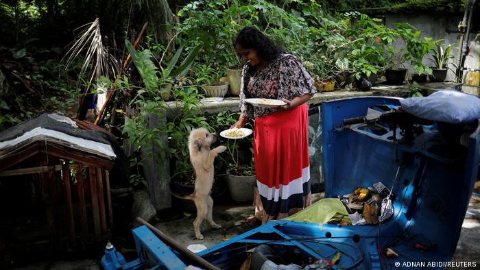 Lasanda Deepthi feeds her dog in Gonapola, Sri Lanka (photo: REUTERS/Adnan Abidia)
