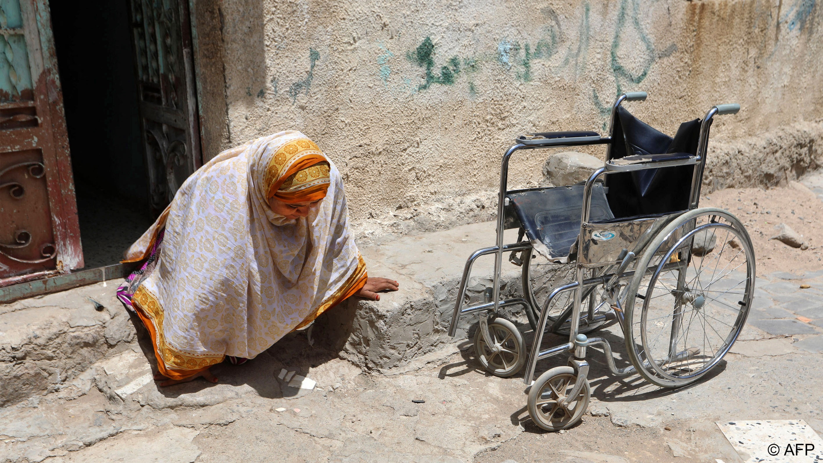  Jamila Qassem Mahyoub, a Yemeni woman whose legs were amputated after stepping on a landmine while herding her sheep in 2017, leaves her house to go to her shop in the city of Taez on 20 March 2019 (photo: AHMAD AL-BASHA AFP/File) 