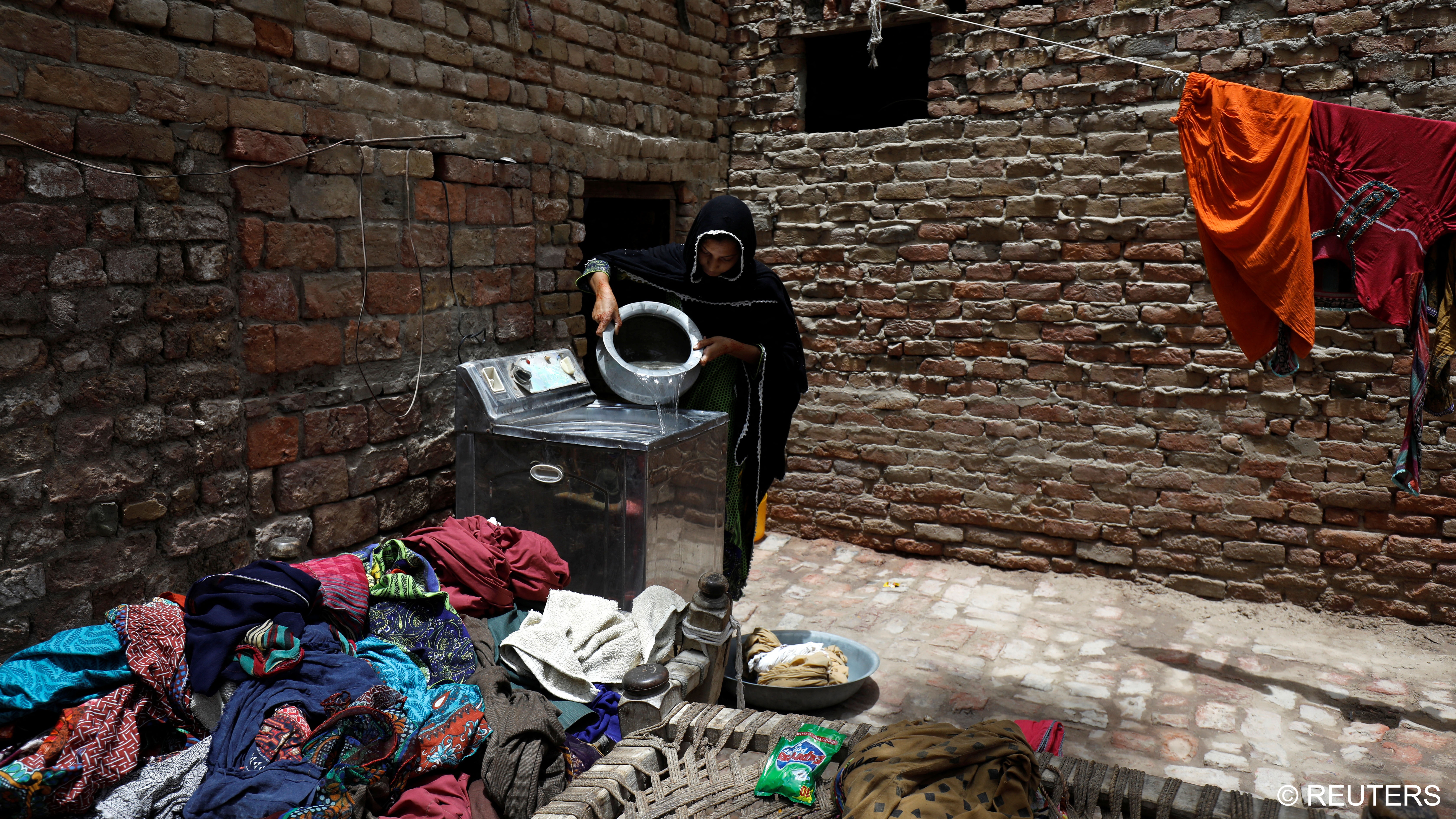 Zahida, 16, washes clothes outside her family home (photo: Reuters/Akhtar Soomro)
